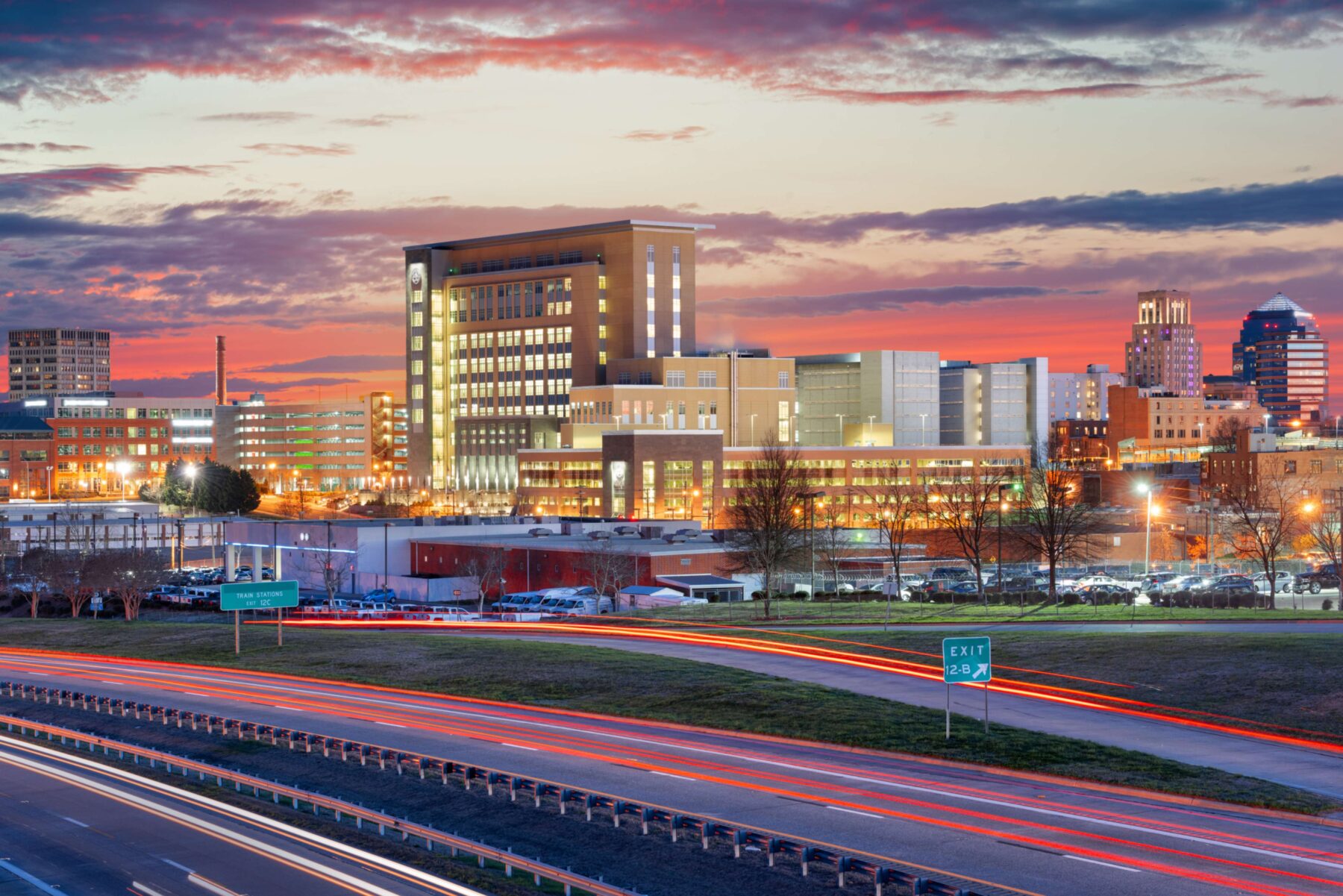 Cityscape at dusk with highway traffic.