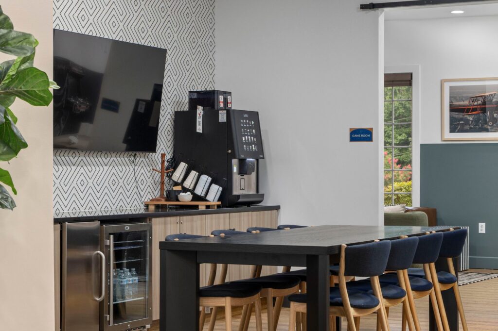 Clubhouse kitchen area with mini fridge, dining table and coffee machine
