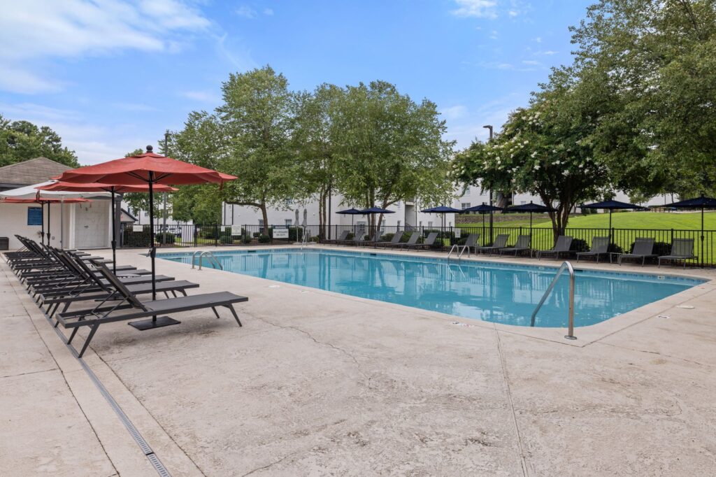 Outdoor pool with patio, lounge chairs and umbrellas overhead