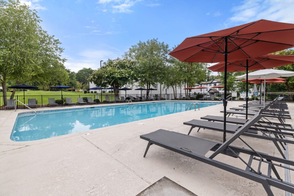 Outdoor pool with patio, lounge chairs and umbrellas overhead