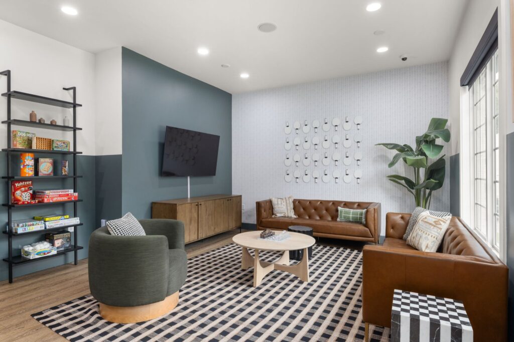 lounge space with sofas and chairs, wall mounted television and bookshelf with various board games