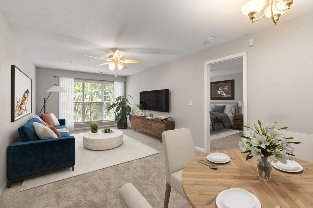 Dining area with carpeted living room connected in open concept floor plan, with view of bedroom